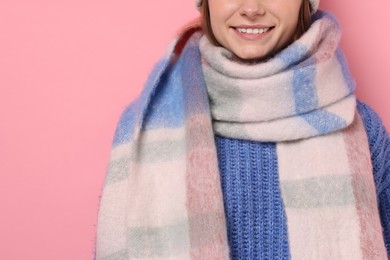 Photo of Woman in warm scarf on pink background, closeup. Space for text