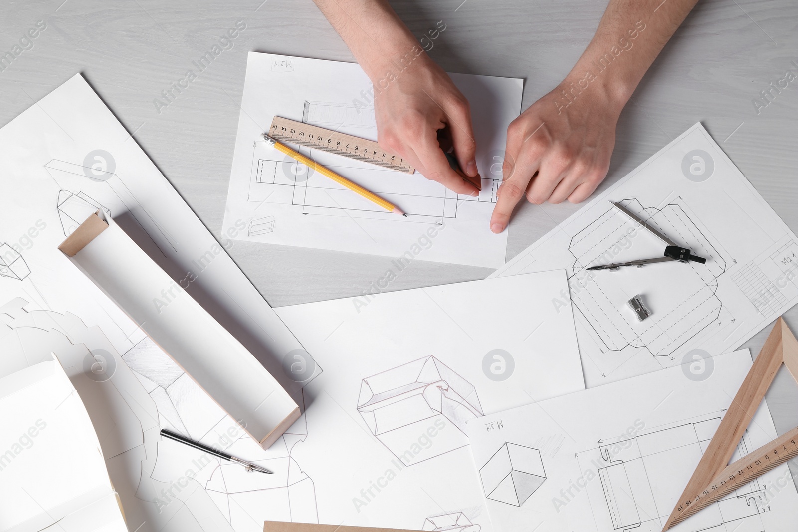 Photo of Man creating packaging design at light wooden table, top view