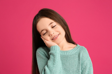 Portrait of cute little girl on pink background