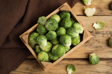 Photo of Fresh Brussels sprouts on wooden table, flat lay