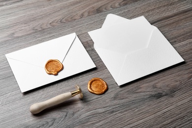 Photo of Envelopes with wax seal and stamp on wooden background