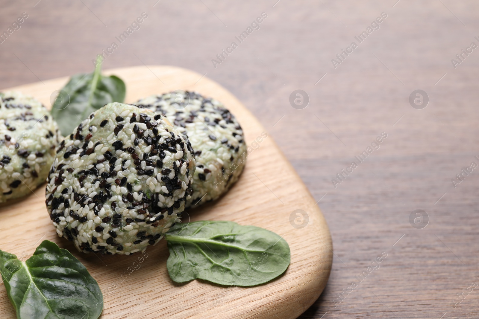 Photo of Tasty vegan cutlets with sesame seeds and spinach on wooden table, closeup. Space for text