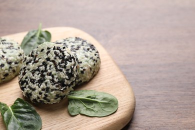 Photo of Tasty vegan cutlets with sesame seeds and spinach on wooden table, closeup. Space for text