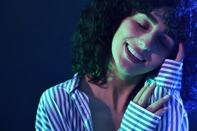 Photo of Beautiful young woman posing on color background in neon lights, closeup