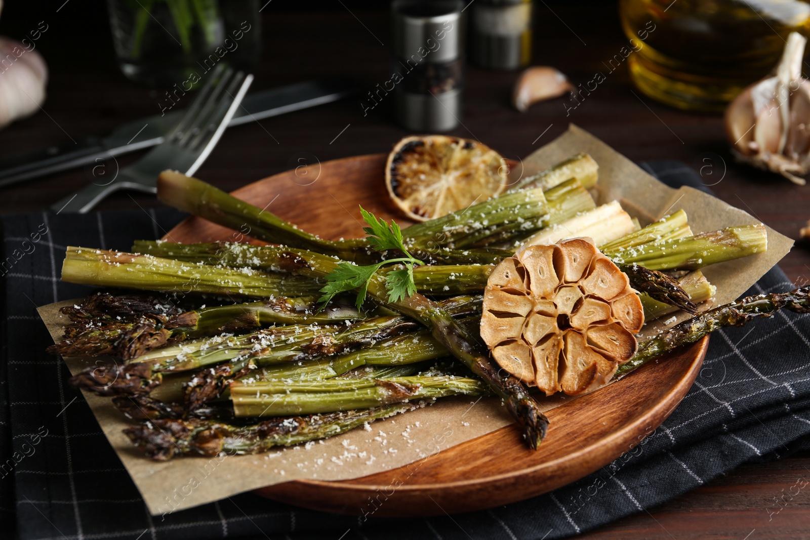 Photo of Oven baked asparagus served with garlic on wooden plate