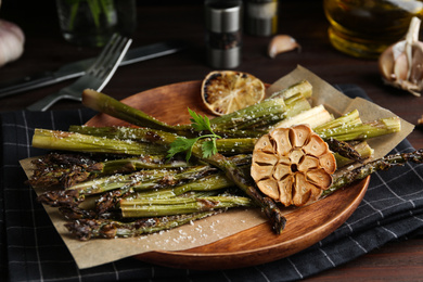 Oven baked asparagus served with garlic on wooden plate