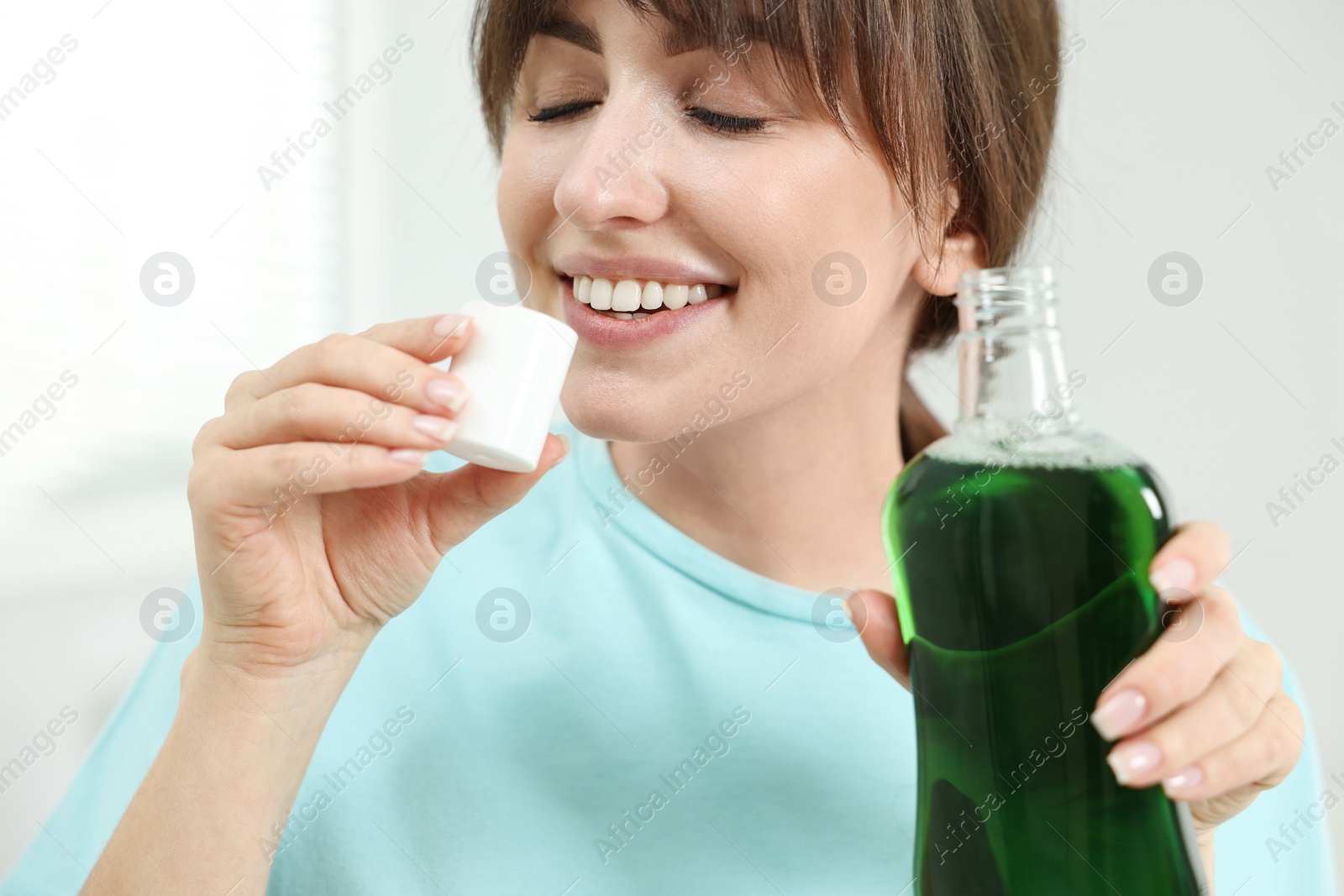 Photo of Young woman using mouthwash on light background, closeup