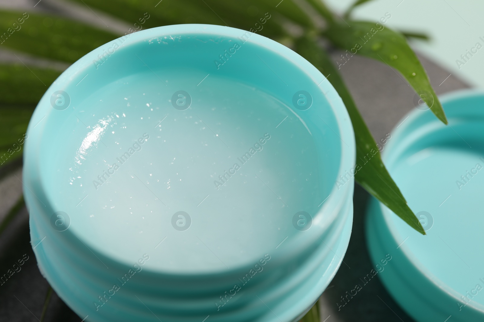 Photo of Lip balm and palm leaf on table, closeup