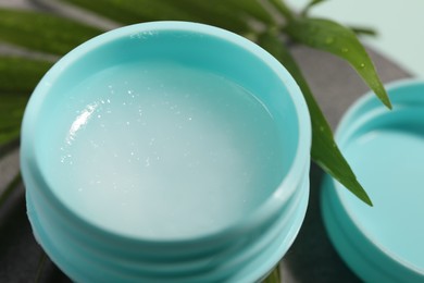 Photo of Lip balm and palm leaf on table, closeup