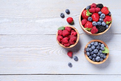 Different fresh ripe berries on light grey wooden table, flat lay. Space for text