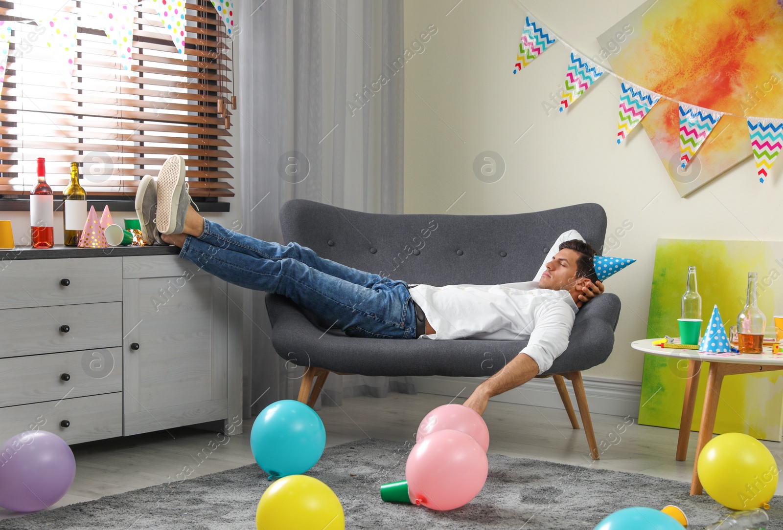 Photo of Man sleeping on sofa in messy room after party