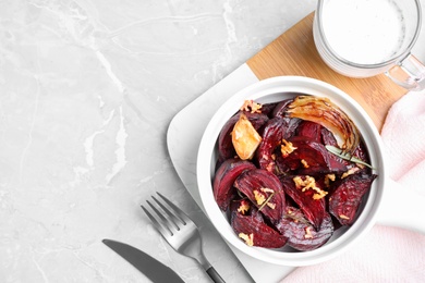 Photo of Roasted beetroot slices, garlic and rosemary on light marble table, flat lay. Space for text