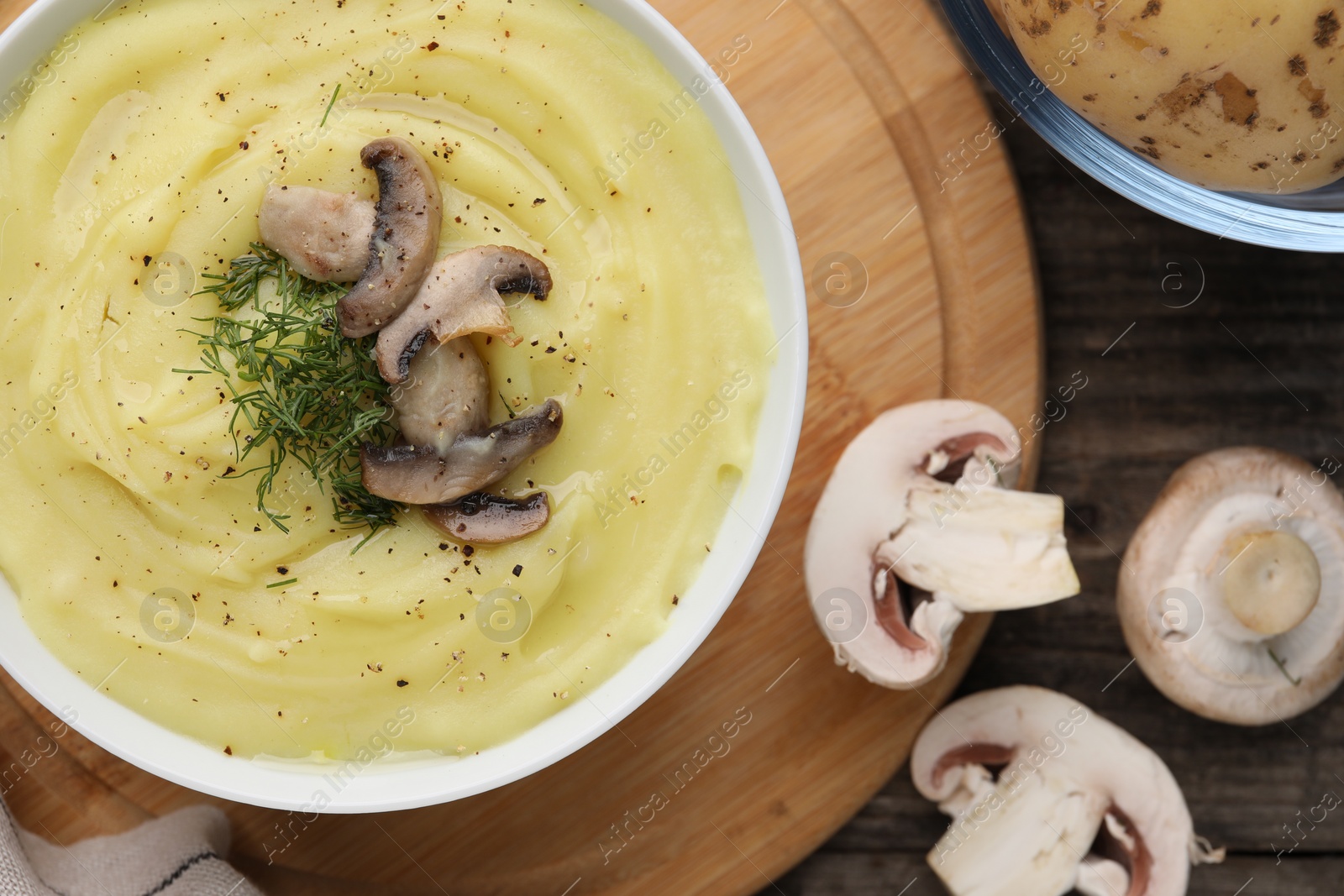 Photo of Bowl of tasty cream soup with mushrooms and dill on wooden table, flat lay
