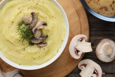 Bowl of tasty cream soup with mushrooms and dill on wooden table, flat lay