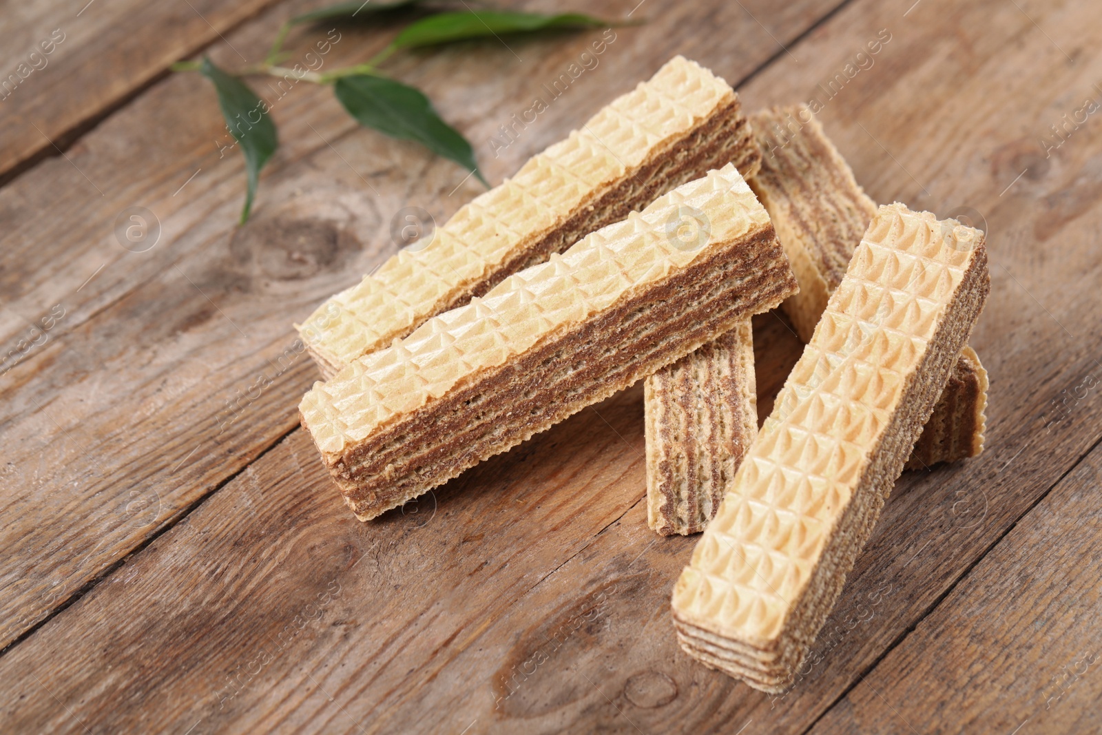 Photo of Delicious crispy wafer sticks on brown wooden background