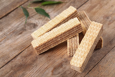 Photo of Delicious crispy wafer sticks on brown wooden background