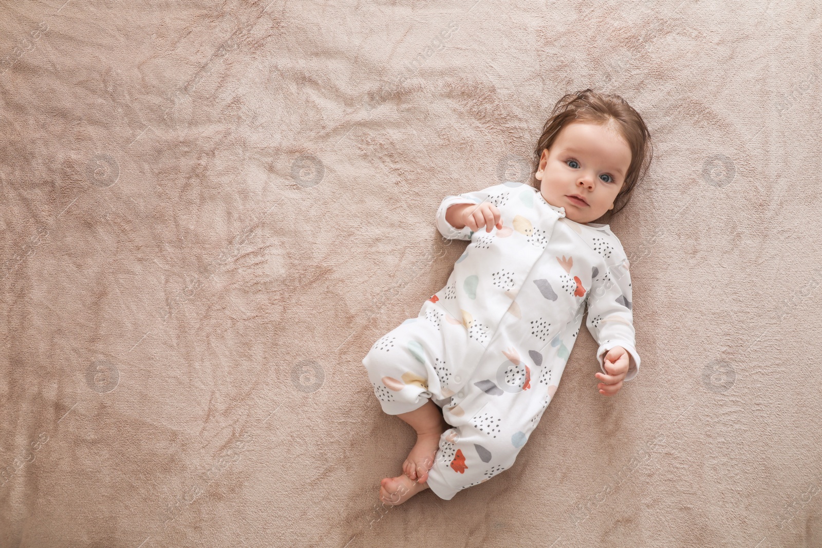 Photo of Cute little baby lying on soft blanket, top view. Space for text