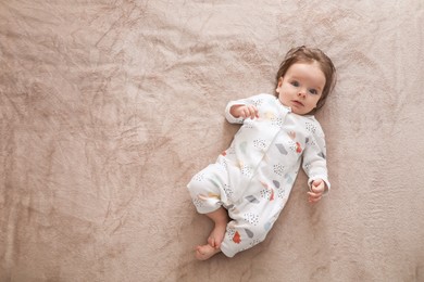 Photo of Cute little baby lying on soft blanket, top view. Space for text