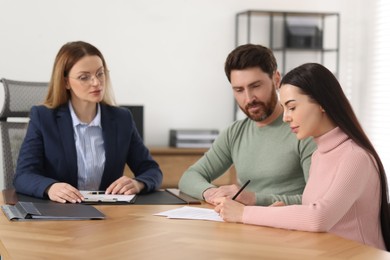 Photo of Happy couple signing document in lawyer's office, selective focus