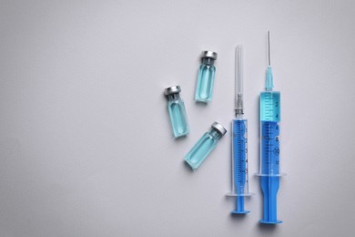 Photo of Disposable syringes with needles and vials on grey background, flat lay. Space for text