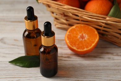 Photo of Bottles of tangerine essential oil on white wooden table, closeup