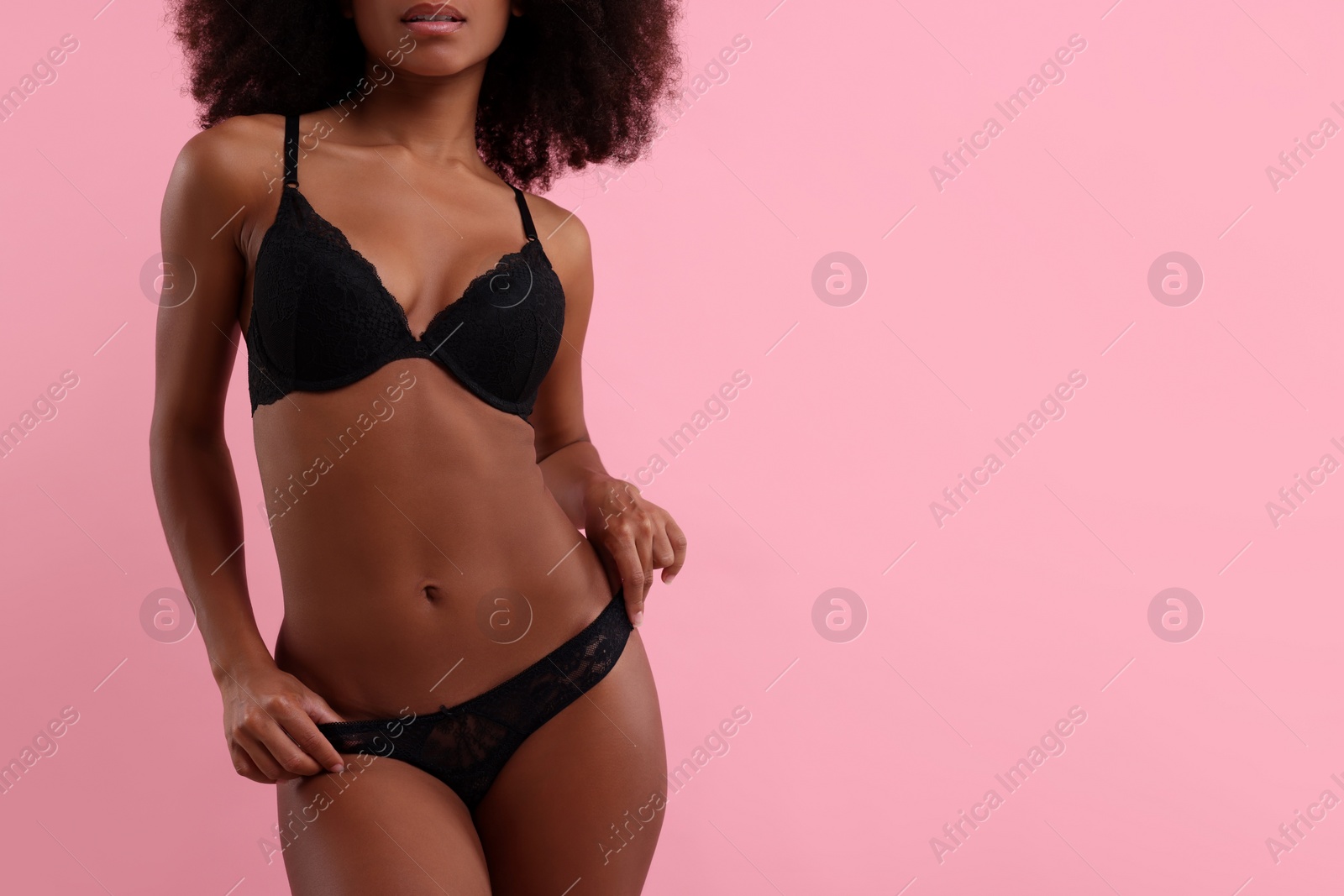 Photo of Woman in elegant black underwear on pink background, closeup. Space for text