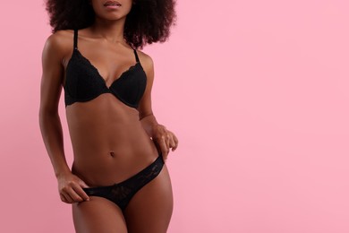 Woman in elegant black underwear on pink background, closeup. Space for text