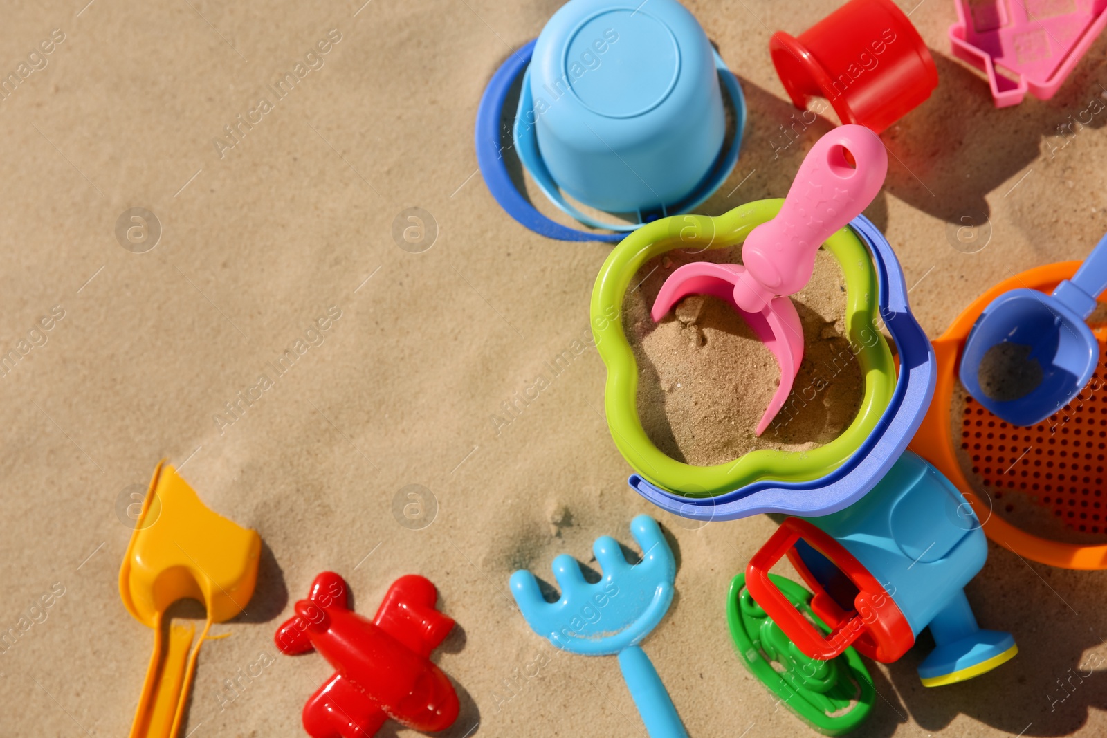 Photo of Set of plastic beach toys on sand, flat lay with space or text. Outdoor play