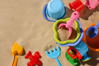 Set of plastic beach toys on sand, flat lay with space or text. Outdoor play