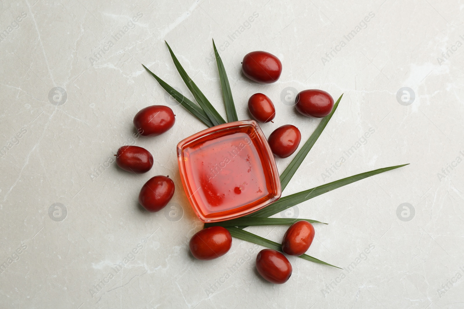 Photo of Palm oil in glass bowl, tropical leaf and fruits on light table, flat lay