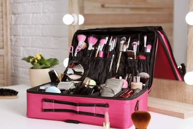 Photo of Beautician case with professional makeup products and tools on dressing table