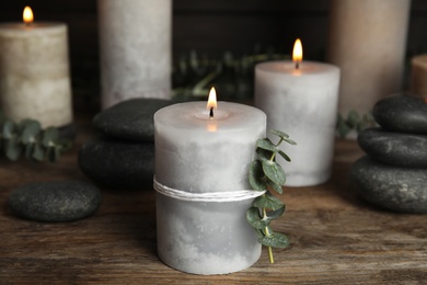 Composition with burning candles, spa stones and eucalyptus on wooden table