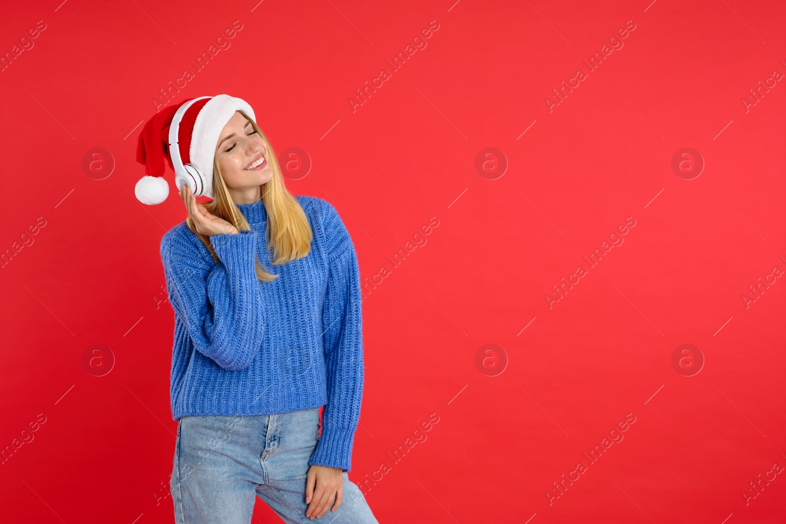 Photo of Happy woman with headphones on red background, space for text. Christmas music