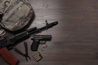 Photo of Flat lay composition with guns and military knapsack on wooden table. Space for text