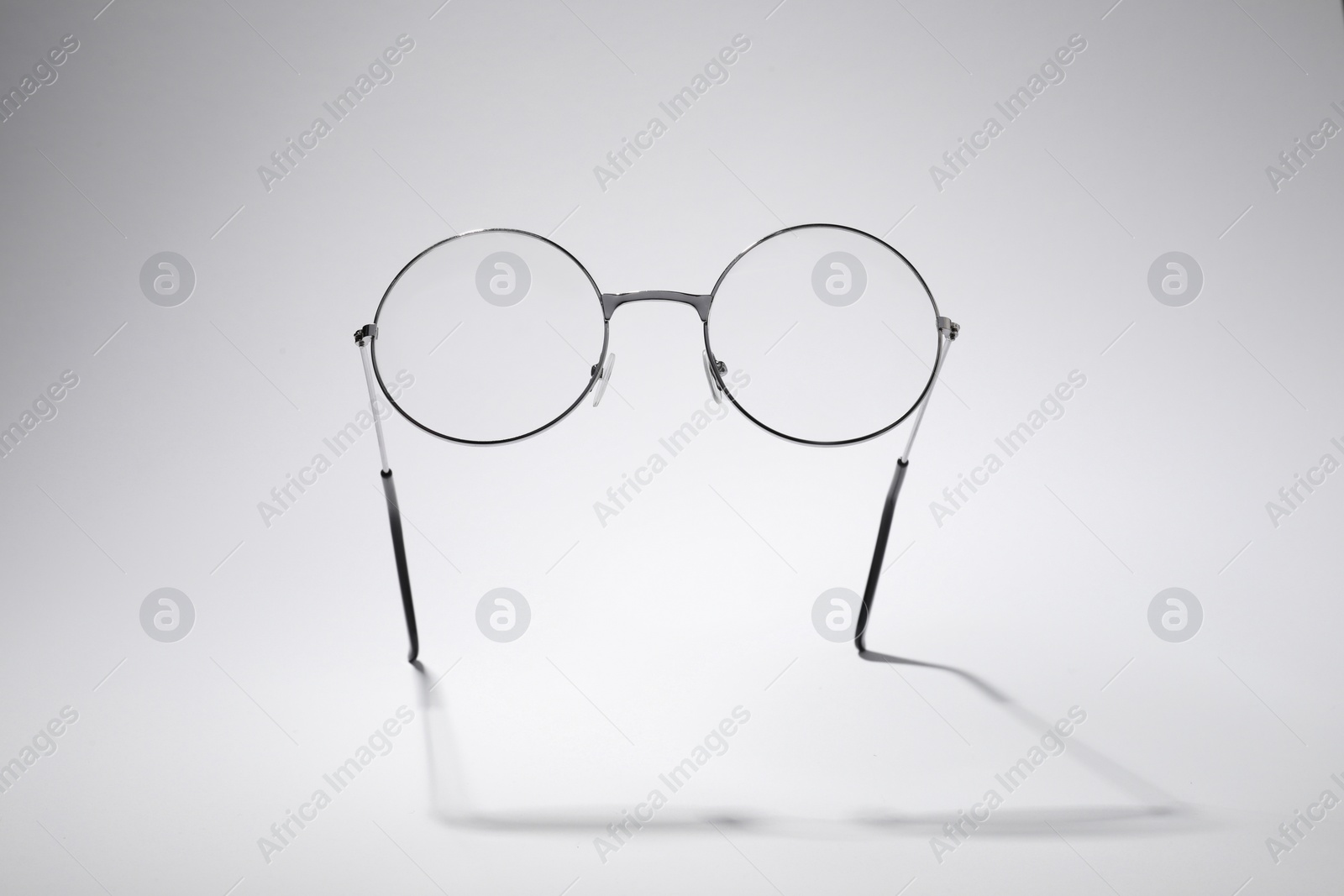 Photo of Stylish pair of glasses with metal frame on light grey background
