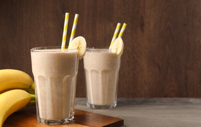 Glasses with banana smoothie on wooden table. Space for text