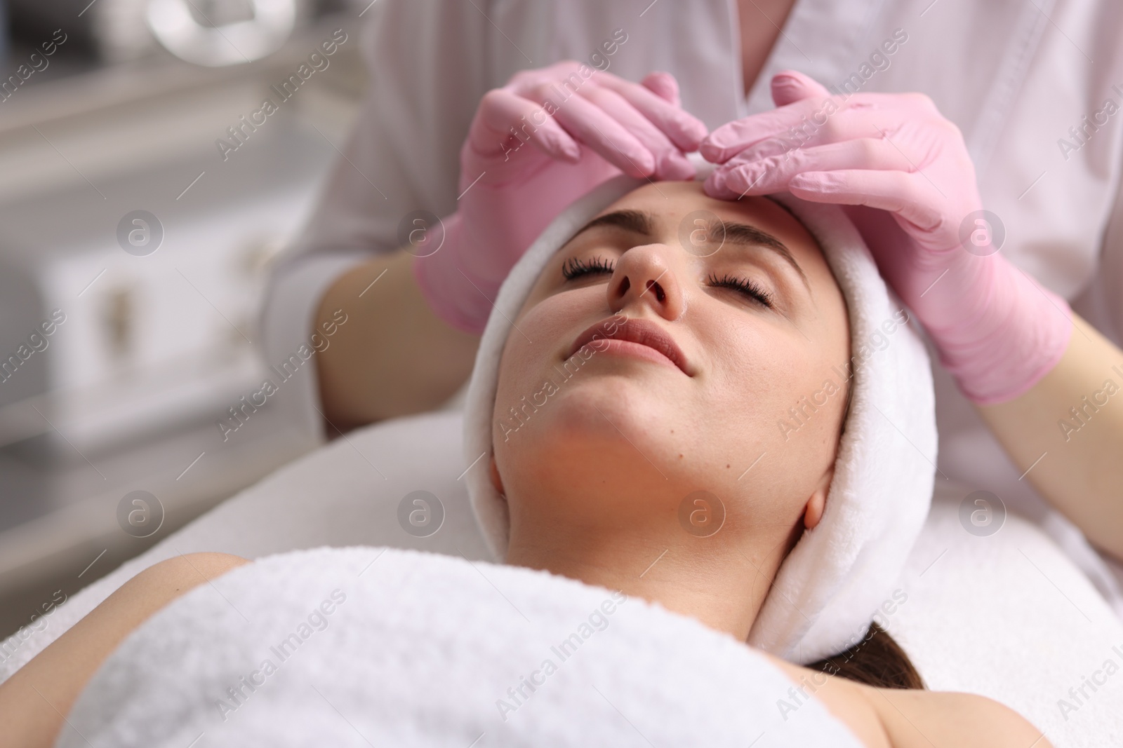 Photo of Cosmetologist making face massage to client in clinic, closeup