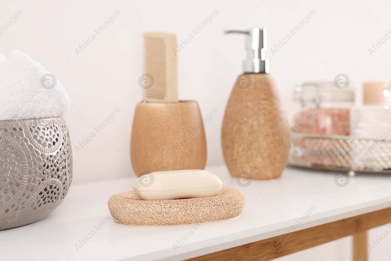 Photo of Different bath accessories and personal care products on table near white wall