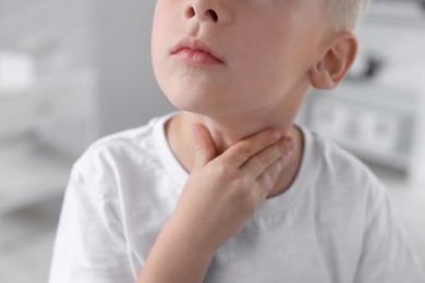 Endocrine system. Little boy doing thyroid self examination indoors, closeup
