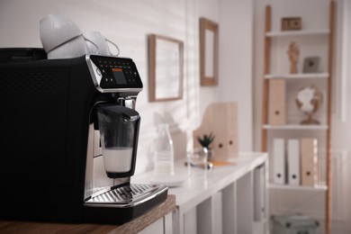 Photo of Modern coffee machine on table in office. Space for text