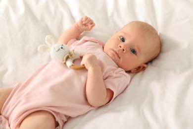 Photo of Cute little baby with toy on white sheets