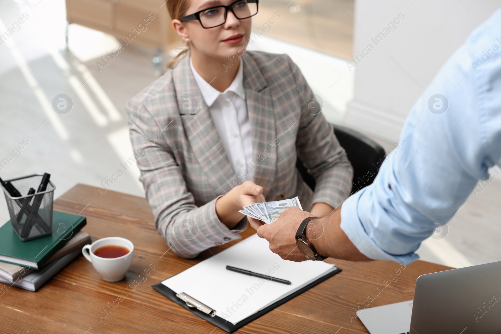 Photo of Man giving bribe money to woman at table, closeup