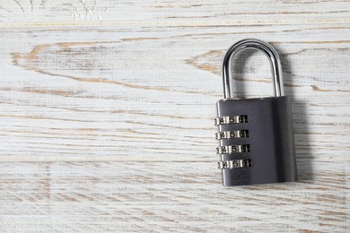 Photo of One steel combination padlock on white wooden table, top view. Space for text