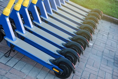 Photo of Many modern electric scooters parked on pavement, closeup. Rental service