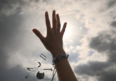 Image of Freedom. Woman with broken chain against cloudy sky, closeup