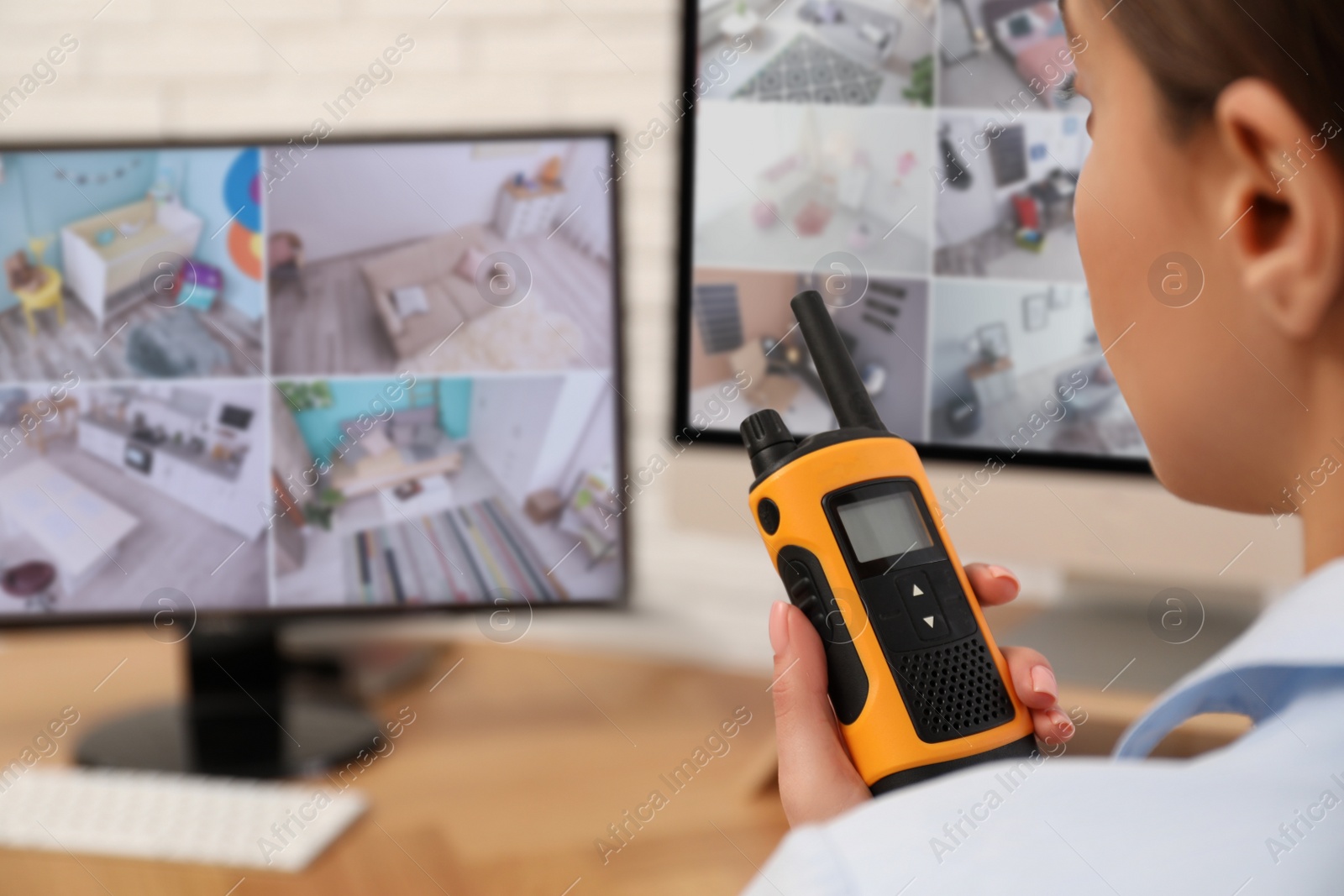 Photo of Female security guard with portable transmitter near monitors at workplace, closeup