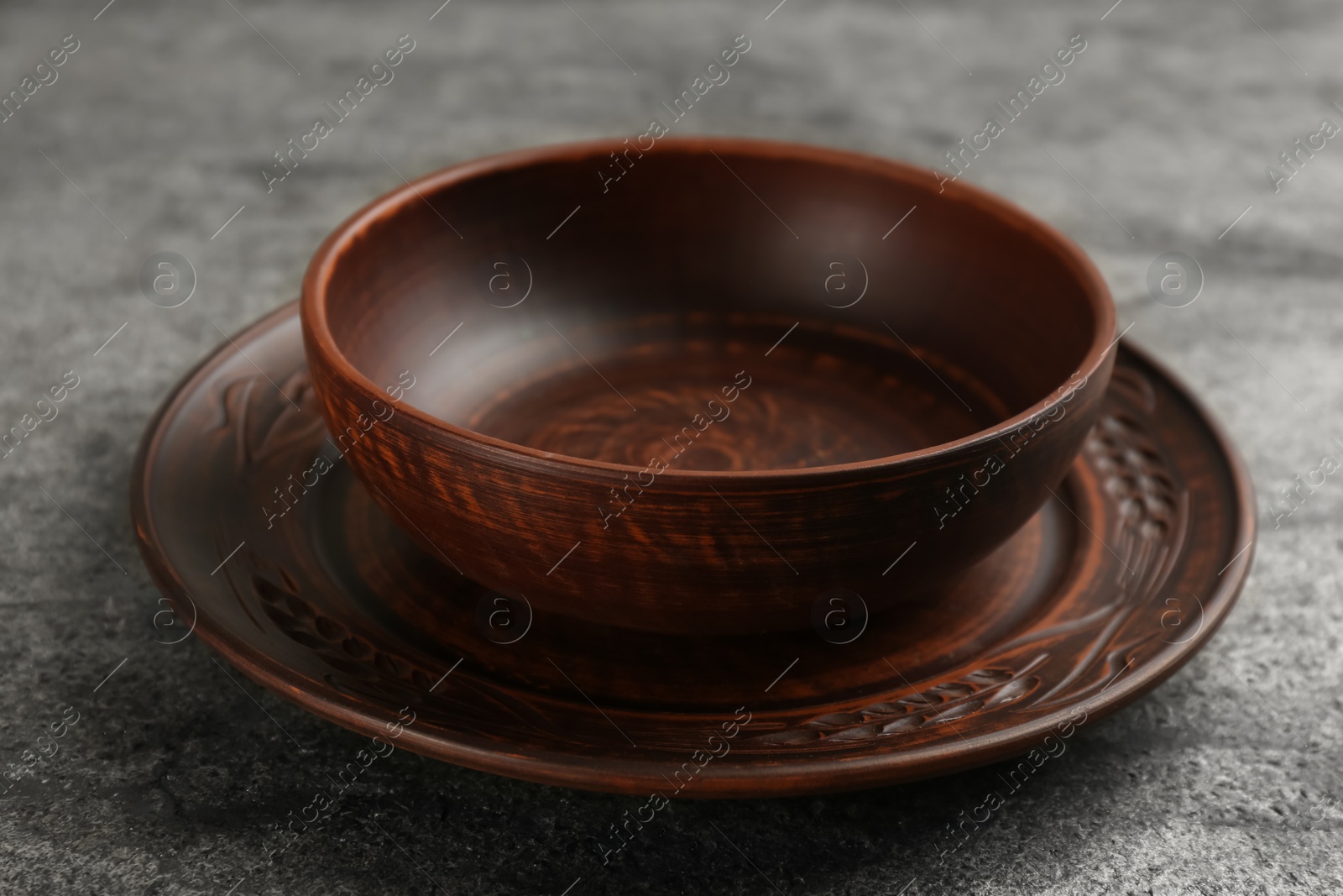 Photo of Clay bowl and plate on grey table. Handmade utensils