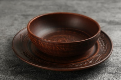 Photo of Clay bowl and plate on grey table. Handmade utensils