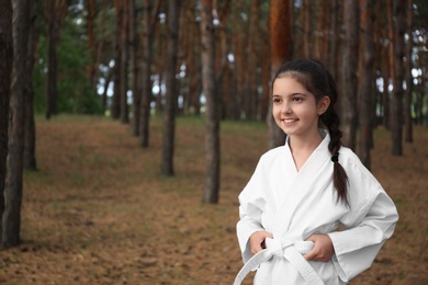 Cute little girl in kimono in forest. Karate practicing