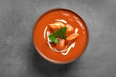 Photo of Bowl of delicious butter chicken on grey background, top view. Traditional indian Murgh Makhani